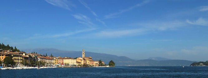 Trip Yoga beliebte Urlaubsziele am Gardasee -  Mit einer Fläche von 370 km² ist der Gardasee der größte See Italiens. Es liegt am Fuße der Alpen und erstreckt sich über drei Staaten: Lombardei, Venetien und Trentino. Die maximale Tiefe des Sees beträgt 346 m, er hat eine längliche Form und sein nördliches Ende ist sehr schmal. Dort ist der See von den Bergen der Gruppo di Baldo umgeben. Du trittst aus deinem gemütlichen Hotelzimmer und es begrüßt dich die warme italienische Sonne. Du blickst auf den atemberaubenden Gardasee, der in zahlreichen Blautönen schimmert - von tiefem Dunkelblau bis zu funkelndem Türkis. Majestätische Berge umgeben dich, während die Brise sanft deine Haut streichelt und der Duft von blühenden Zitronenbäumen deine Nase kitzelt. Du schlenderst die malerischen, engen Gassen entlang, vorbei an farbenfrohen, blumengeschmückten Häusern. Vereinzelt unterbricht das fröhliche Lachen der Einheimischen die friedvolle Stille. Du fühlst dich wie in einem Traum, der nicht enden will. Jeder Schritt führt dich zu neuen Entdeckungen und Abenteuern. Du probierst die köstliche italienische Küche mit ihren frischen Zutaten und verführerischen Aromen. Die Sonne geht langsam unter und taucht den Himmel in ein leuchtendes Orange-rot - ein spektakulärer Anblick.